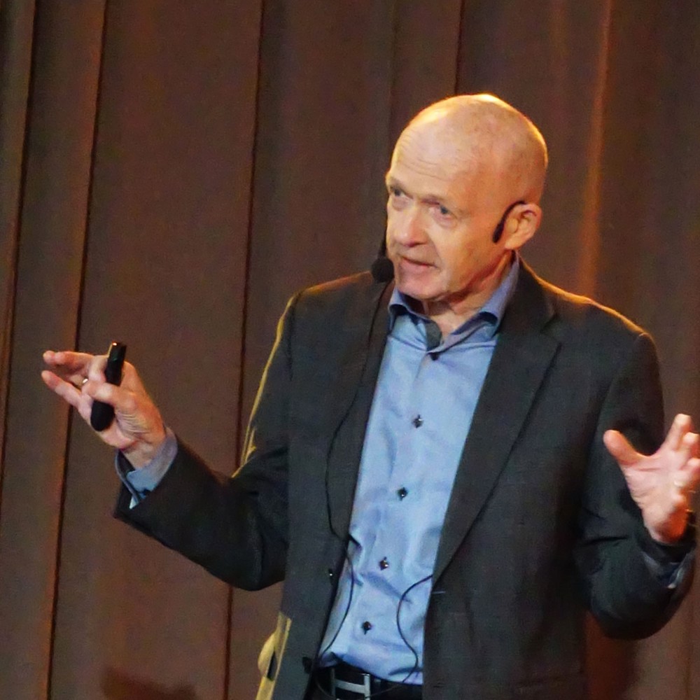 mann på scene, armene ut, gestikulerer, mikrofon, snakker