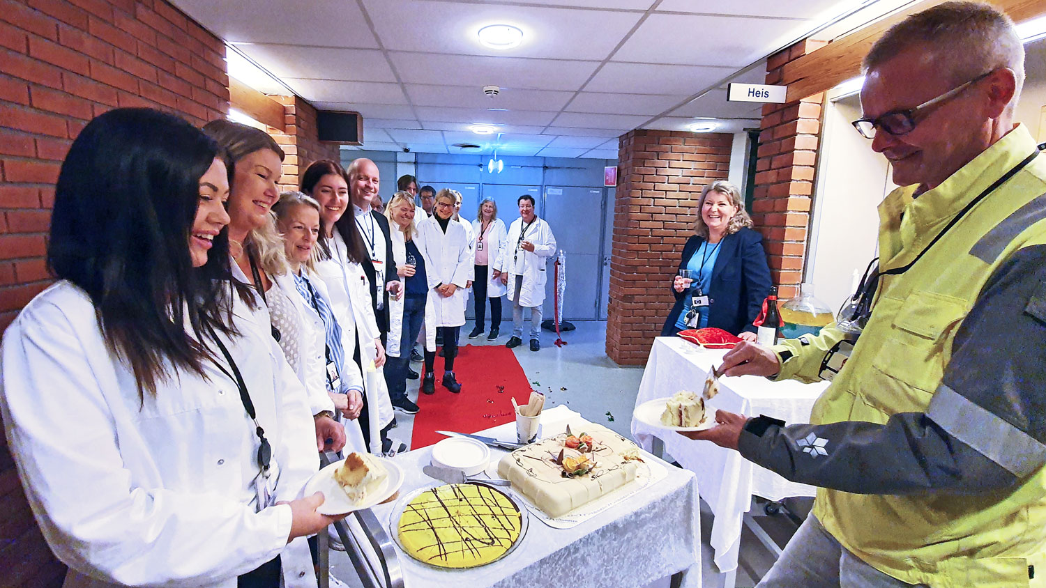 employees in white lab coates celebrating eating cake