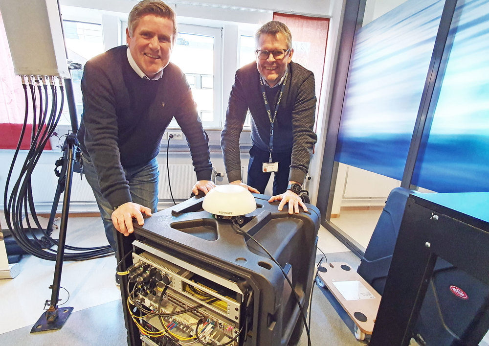 two men leaning towards a 80 cm tall black network box.