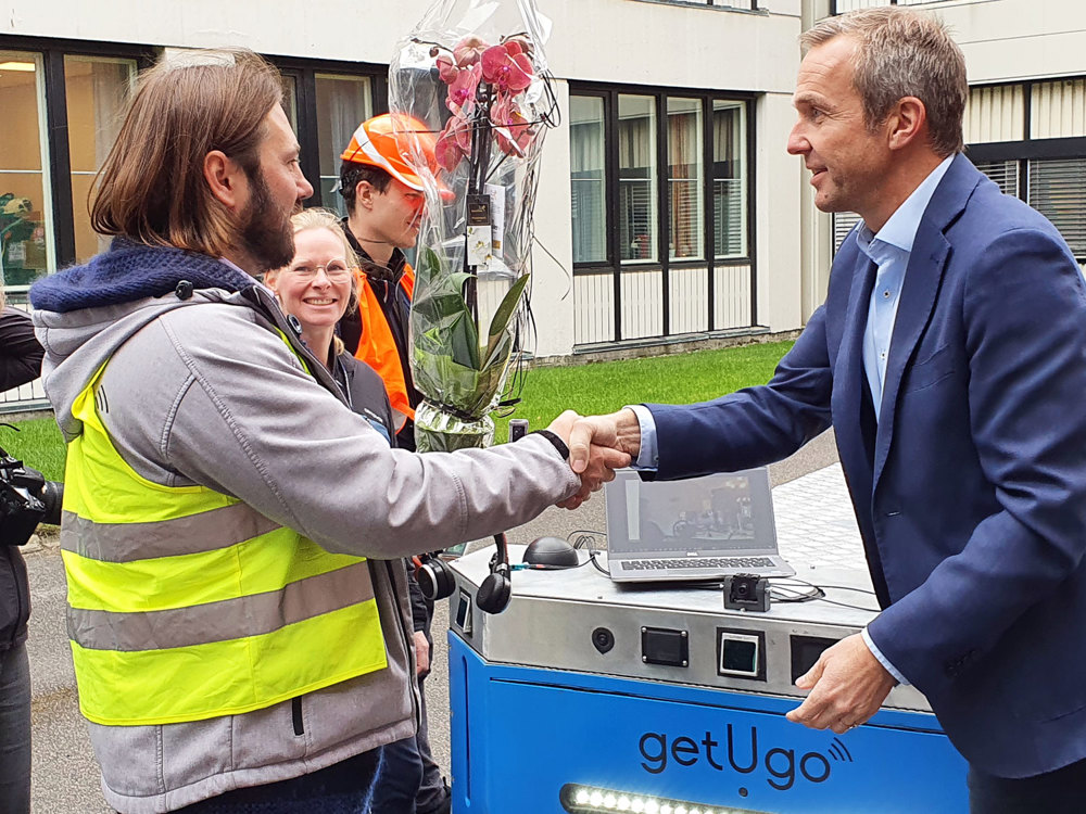 two men shaking hands over robot