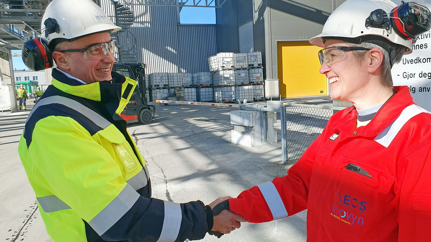 two persons, shaking hands, white helmets, process industry, outdoors