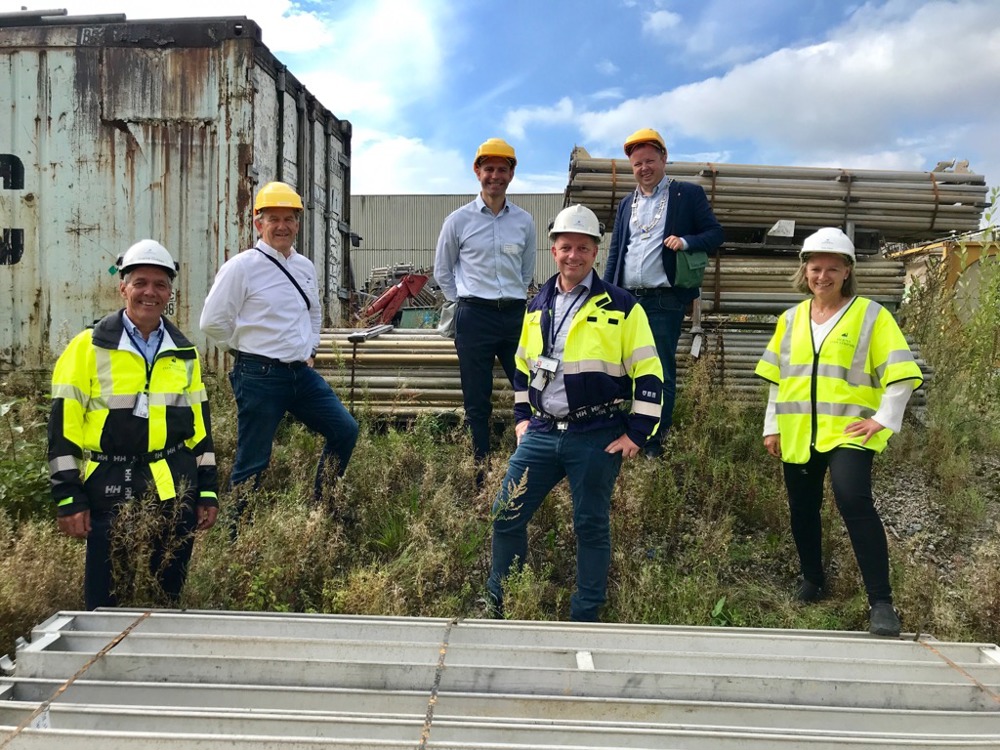 six people standing out doors by a scaffolding storage