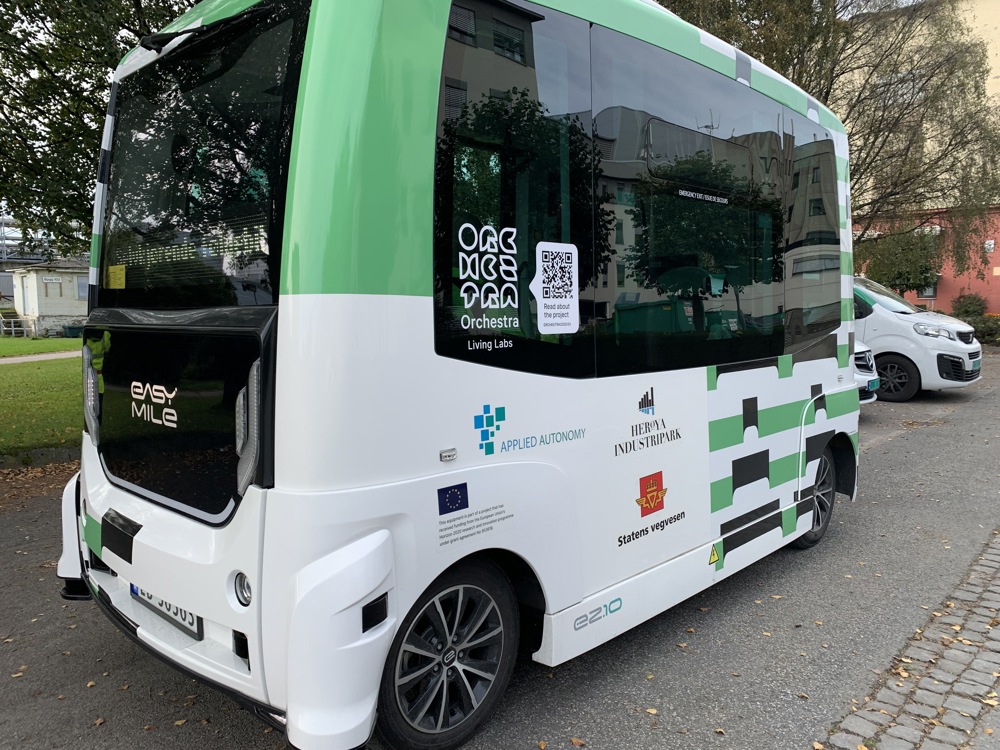 small mini bus, autonomous, self-driving, white and green, parked along a road in the industrial park