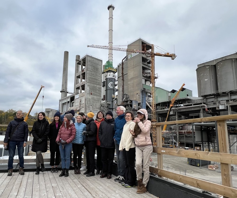 a group of people standing on a deck overlooking an industrial area and a building site for the construction of a carbon capture plant