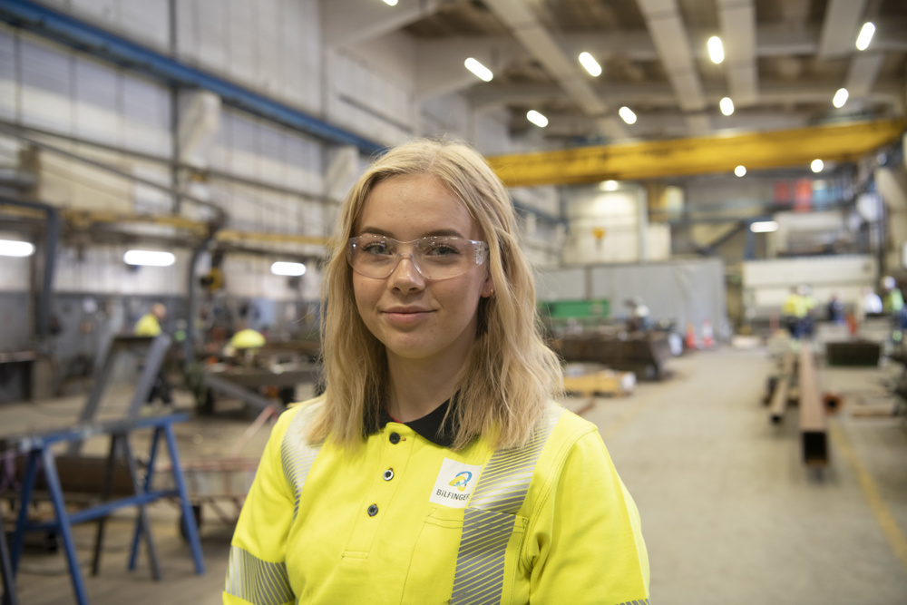 ung blond kvinne med vernebriller i verkstedhall