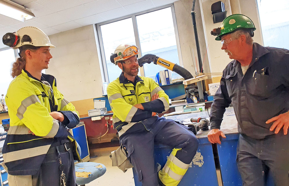 three men chatting in a workshop