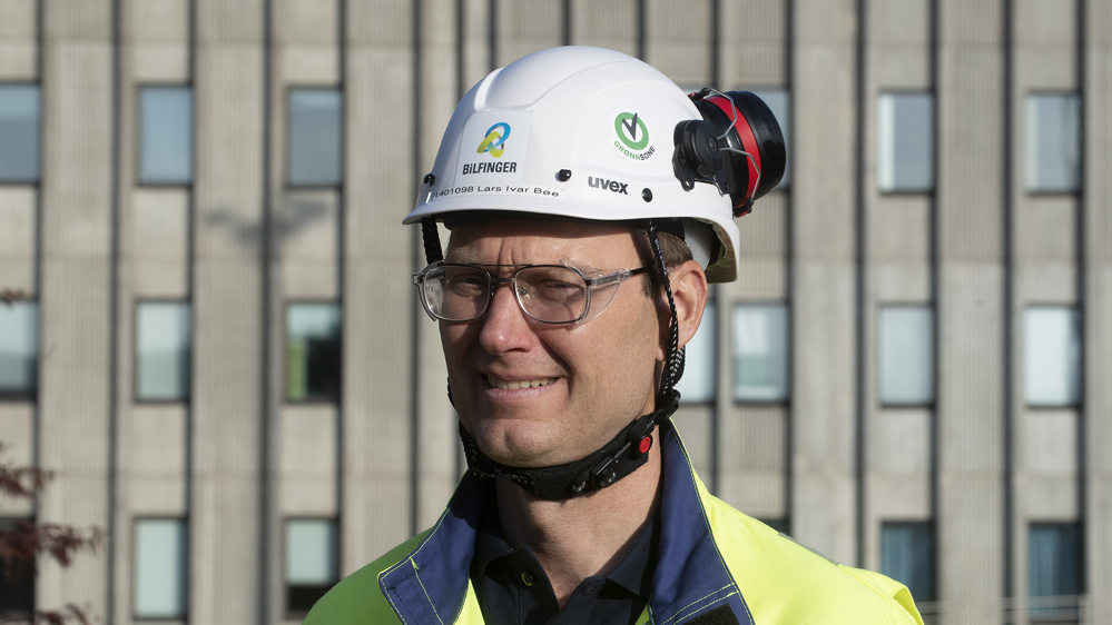 portrait, man, white helmet, standing in front of a big concrete building, many windows