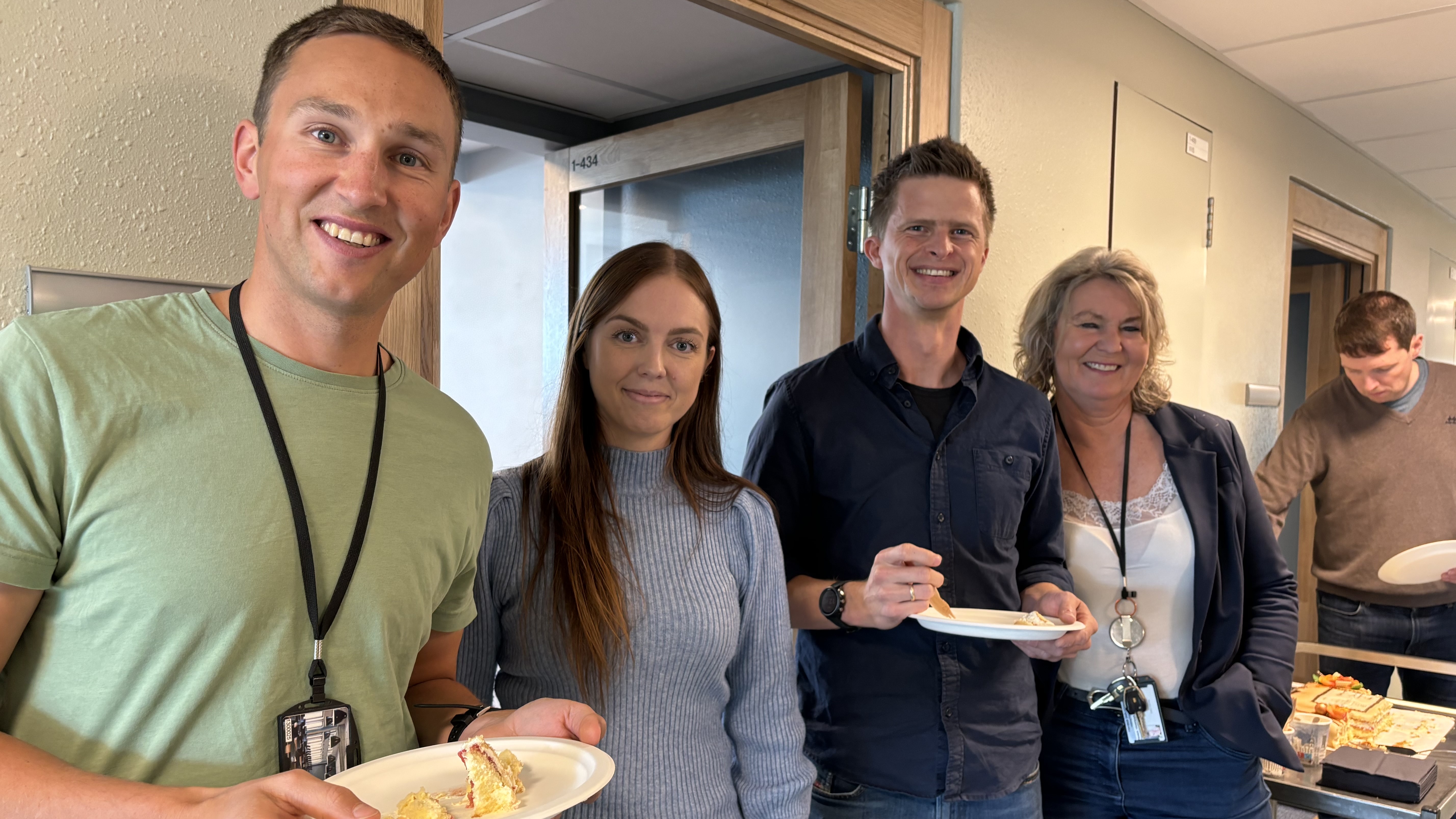 four persons, posing, eating cake, office environment