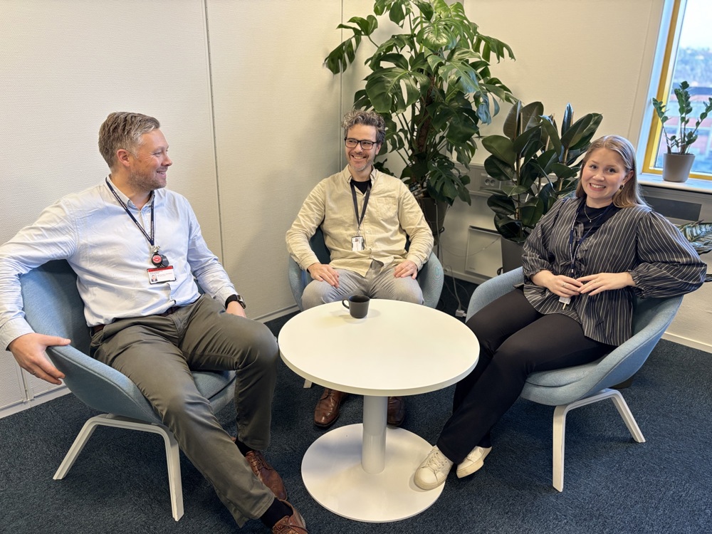 tre personer sitter i stoler rundt et rundt bord