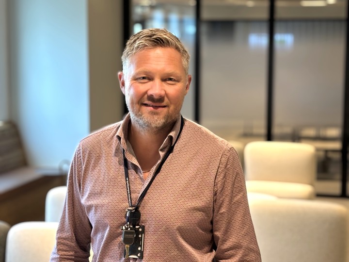 portrett av mann, møtelokale i bakgrunnen.