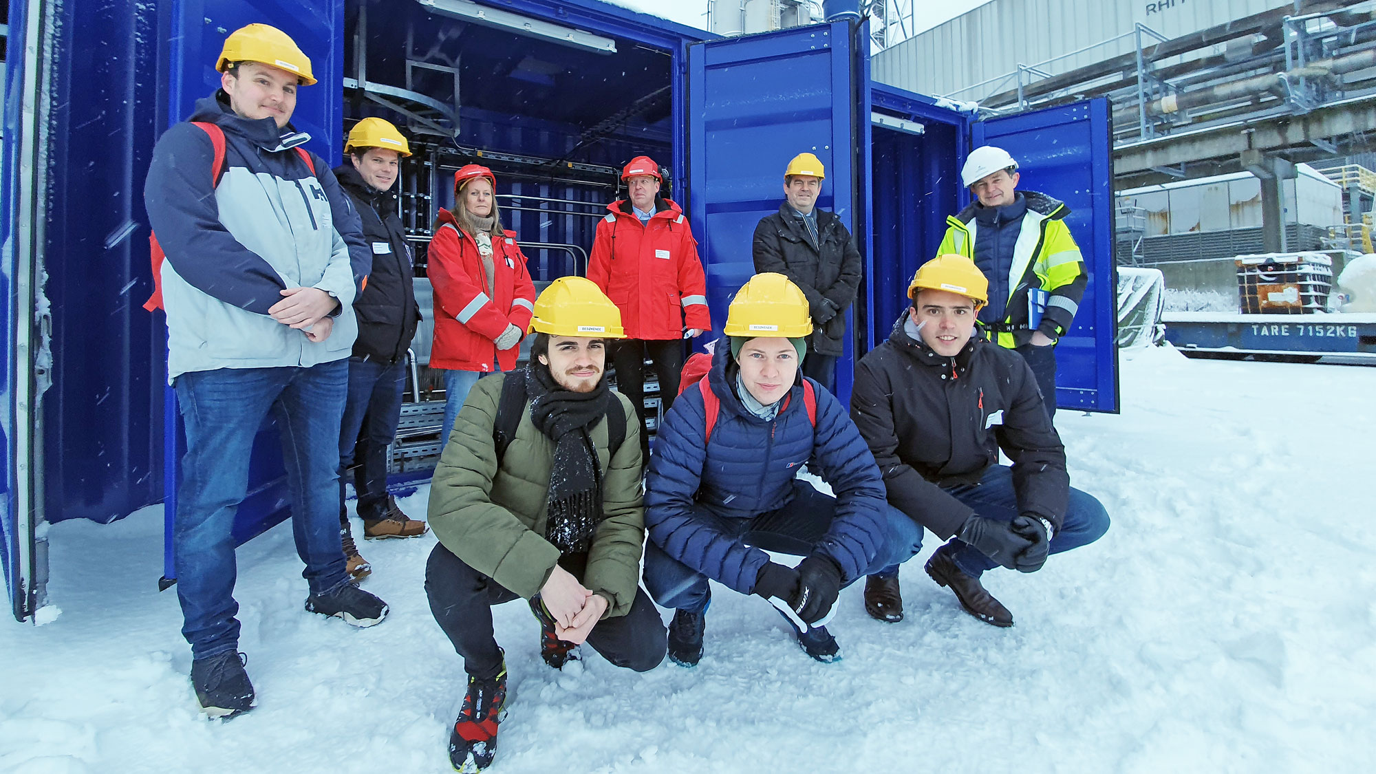 group of people standing outside a blu research container with open doors.