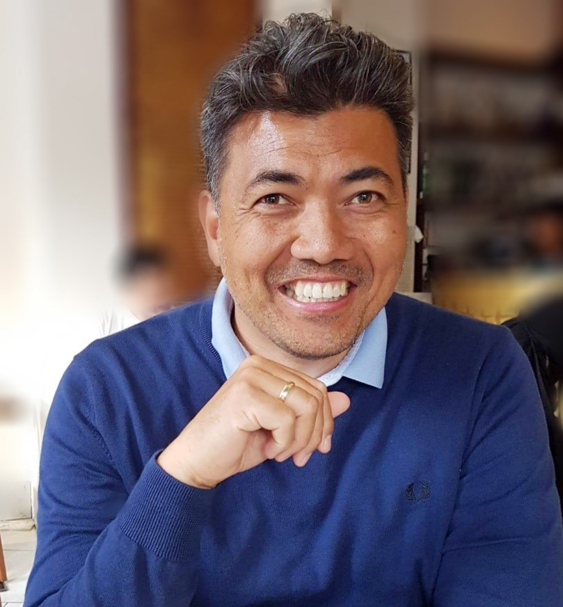 portrait of man in blue jumper, posing, his right hand in front of his chest